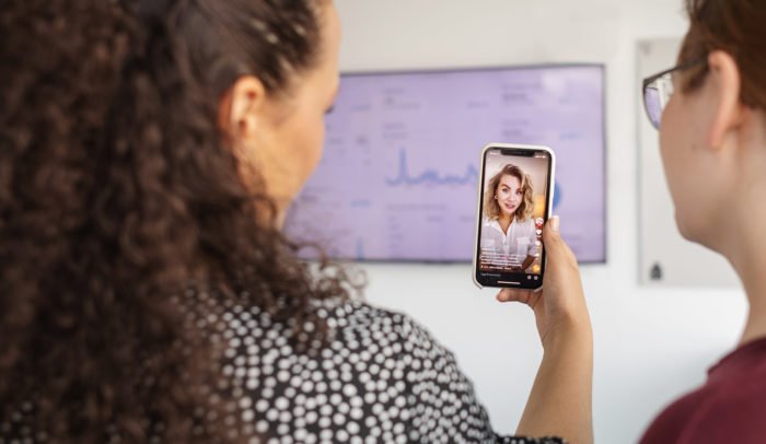 Två kvinnor som kollar på TikTok på mobilen
