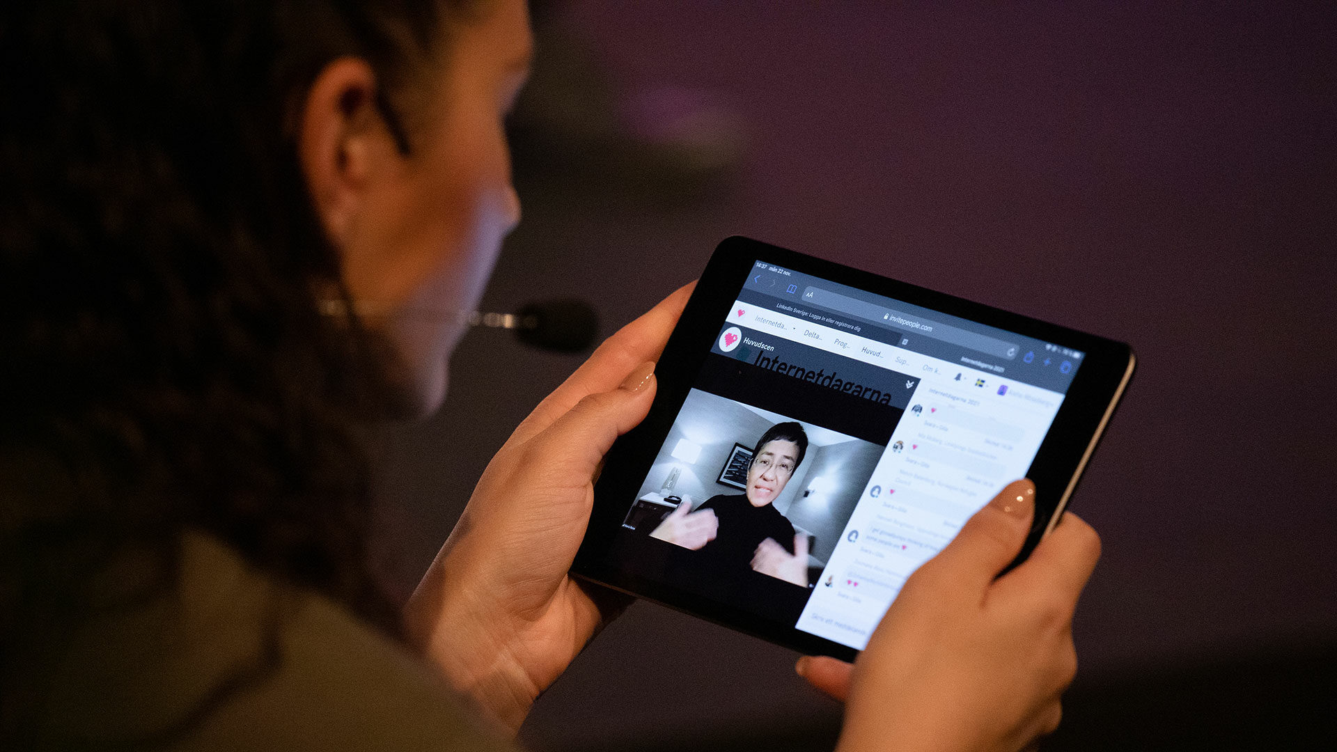 En kvinna sitter och tittar på Internetdagarna på en surfplatta.