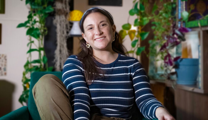 Keynotetalaren Abbie Richards sitter i en soffa framför gröna växter