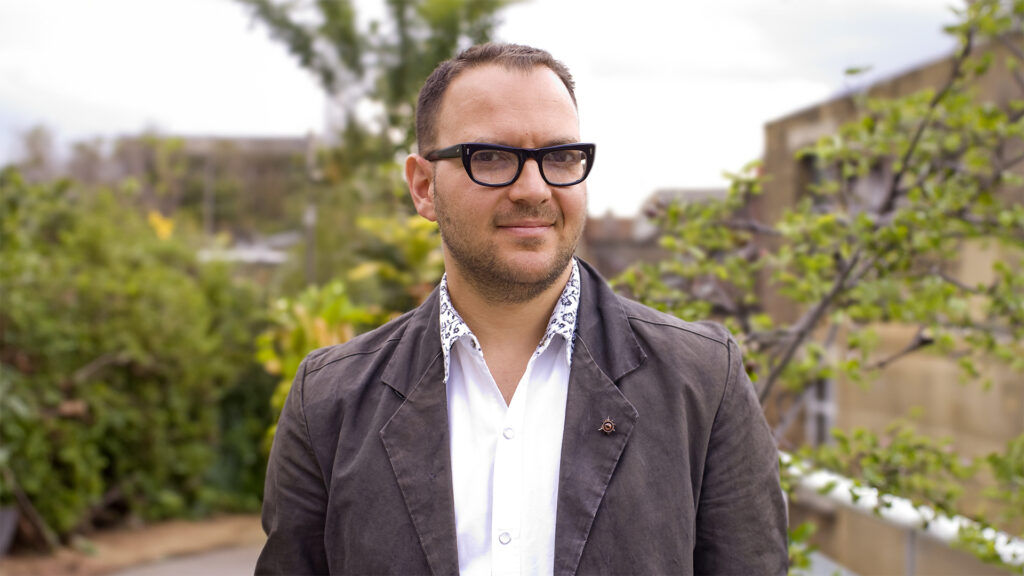 Porträtt av huvudtalare Cory Doctorow i utomhusmiljö.